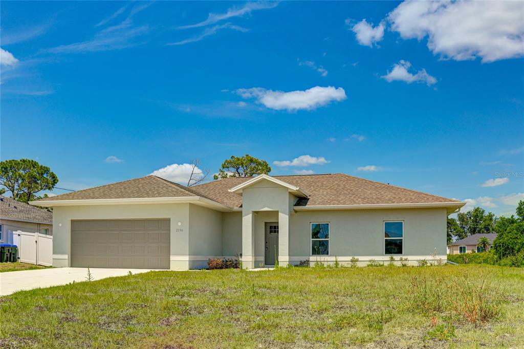 A single-story house with a beige stucco exterior, a two-car garage, and a shingled roof — 2194 BRANCUSI AVENUE, NORTH PORT, FL