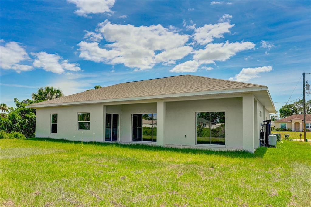 The exterior rear view of a single-story house with a covered patio and sliding doors — 2194 BRANCUSI AVENUE, NORTH PORT, FL