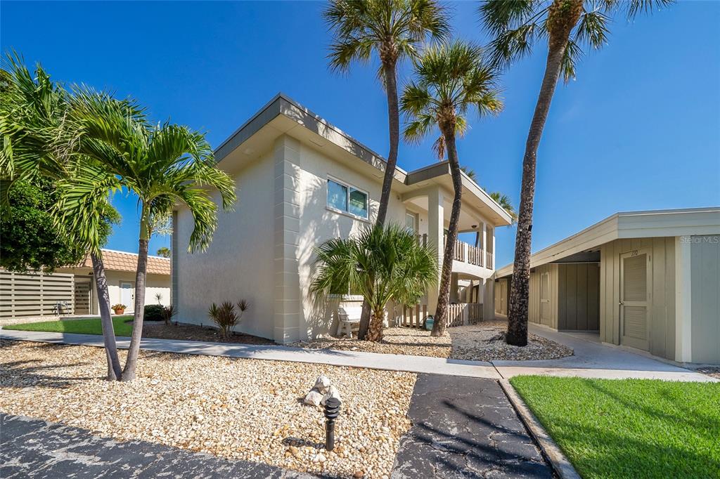 A two-story building with a flat roof, palm trees, and a gravel front yard — 6300 FLOTILLA DRIVE UNIT 107, BRADENTON BEACH, FL