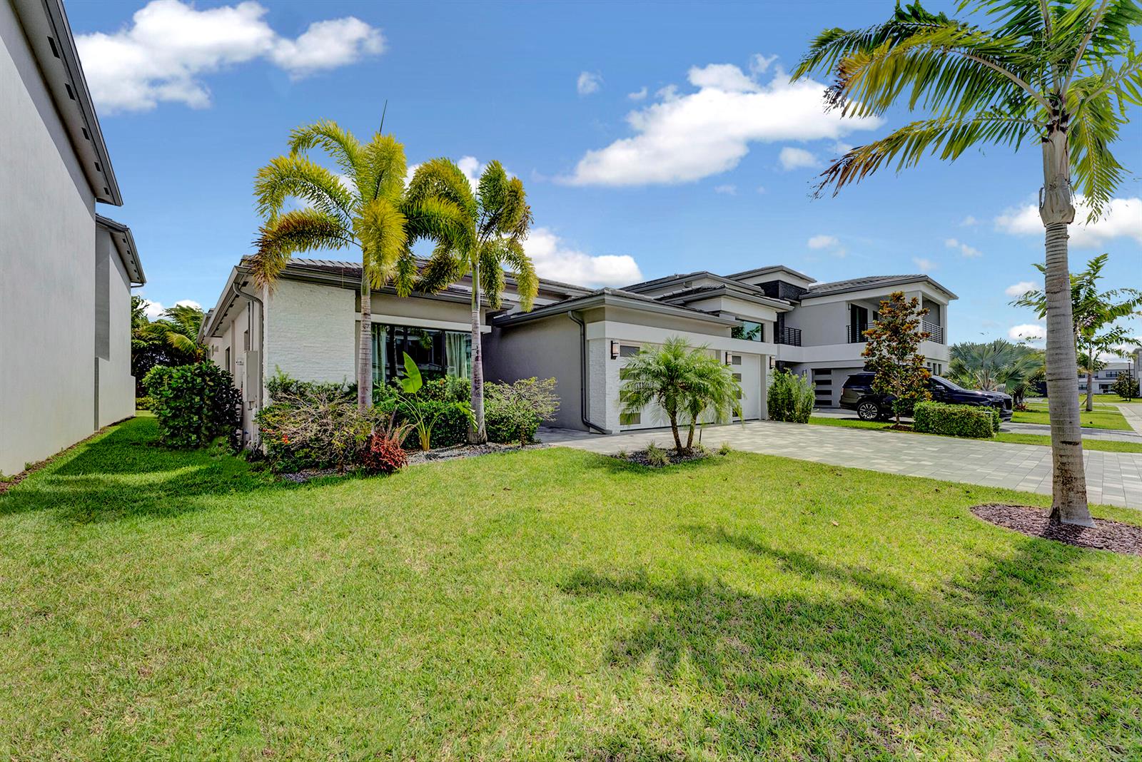 A modern single-story house with a paved driveway, palm trees, and a green lawn — 8533 Ganton Drive, Boca Raton FL 33434, BOCA RATON, FL
