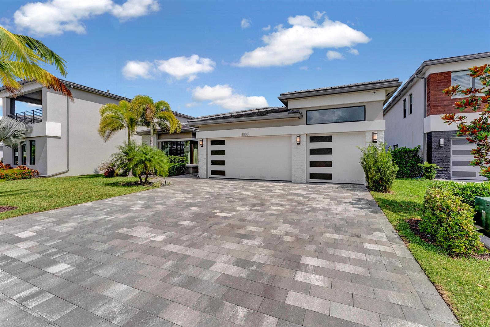 A modern single-story house with a paved driveway, two-car garage, and palm trees — 8533 Ganton Drive, Boca Raton FL 33434, BOCA RATON, FL