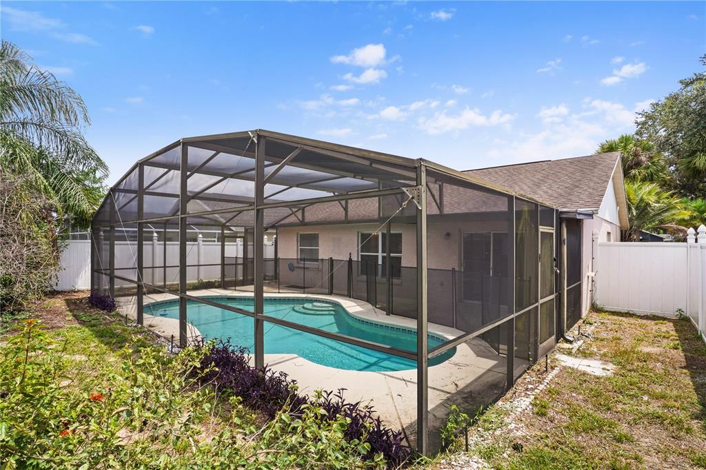 A backyard swimming pool enclosed by a screened lanai next to a single-story house — 1512 OAK HILL TRAIL, KISSIMMEE, FL