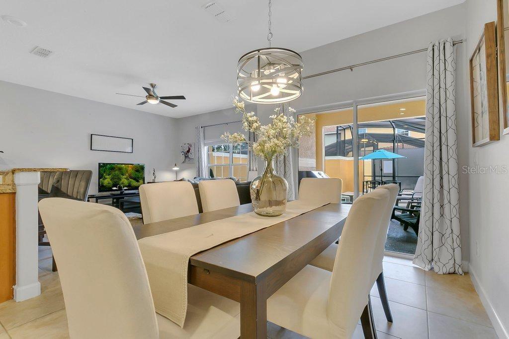 A dining area features a wooden table, upholstered chairs, a drum pendant light, and patio access — 8979 CALIFORNIA PALM ROAD, KISSIMMEE, FL