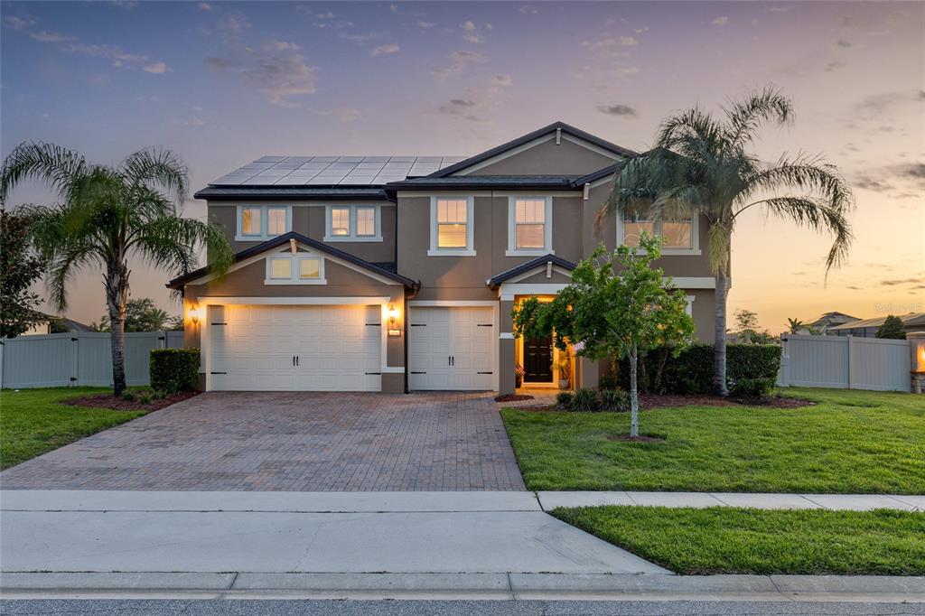 A two-story suburban house with a paved driveway, solar panels, and palm trees at dusk — 3344 KAYAK WAY, ORLANDO, FL