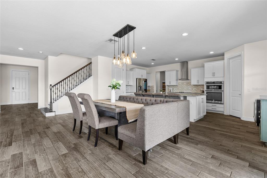 A dining area with a tufted bench and chairs sits in front of an open kitchen — 3344 KAYAK WAY, ORLANDO, FL