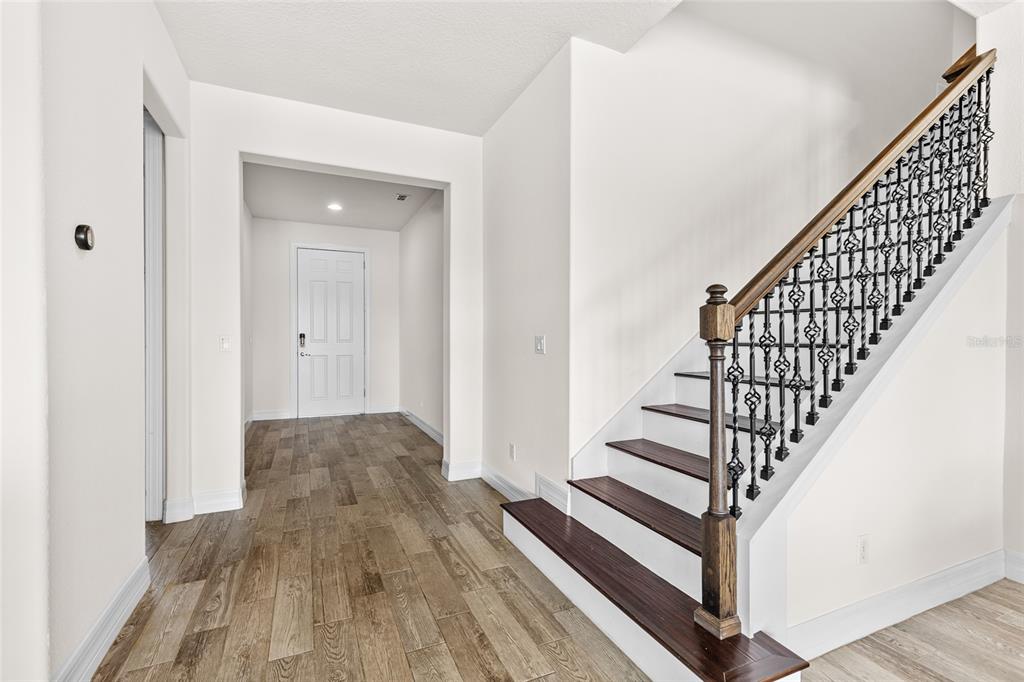 A foyer features wood-look tile flooring, white walls, and a staircase with a wooden railing — 3344 KAYAK WAY, ORLANDO, FL