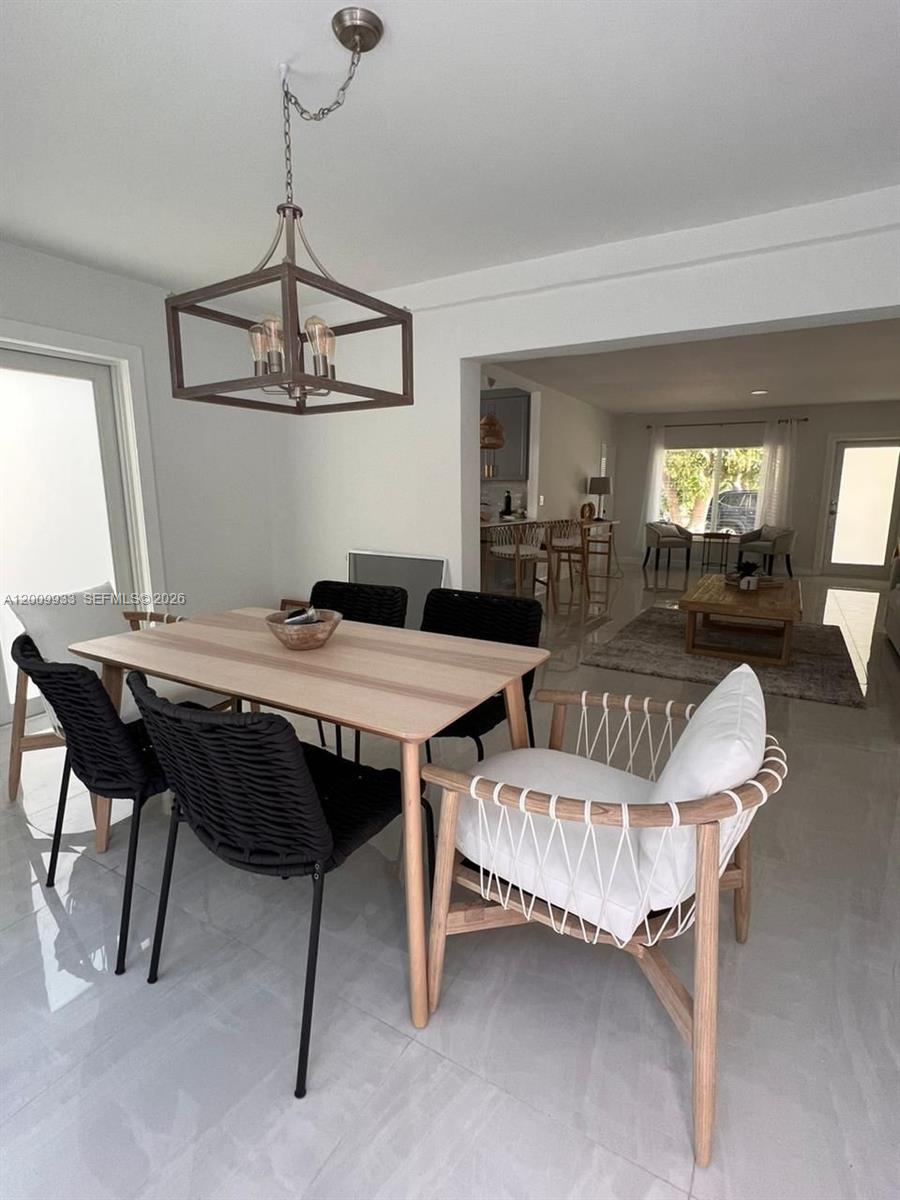 A dining area with a wooden table and chairs sits adjacent to an open living room — 1030 NE 83rd St # 0, Miami FL 33138, MIAMI, FL