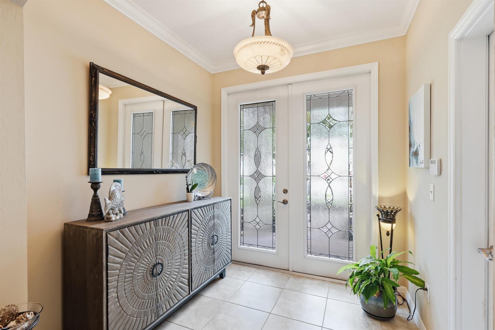 A foyer features a wooden console table, a large mirror, and double glass-paneled entry doors — 1517 Birdie Drive, Naples FL 34120, NAPLES, FL