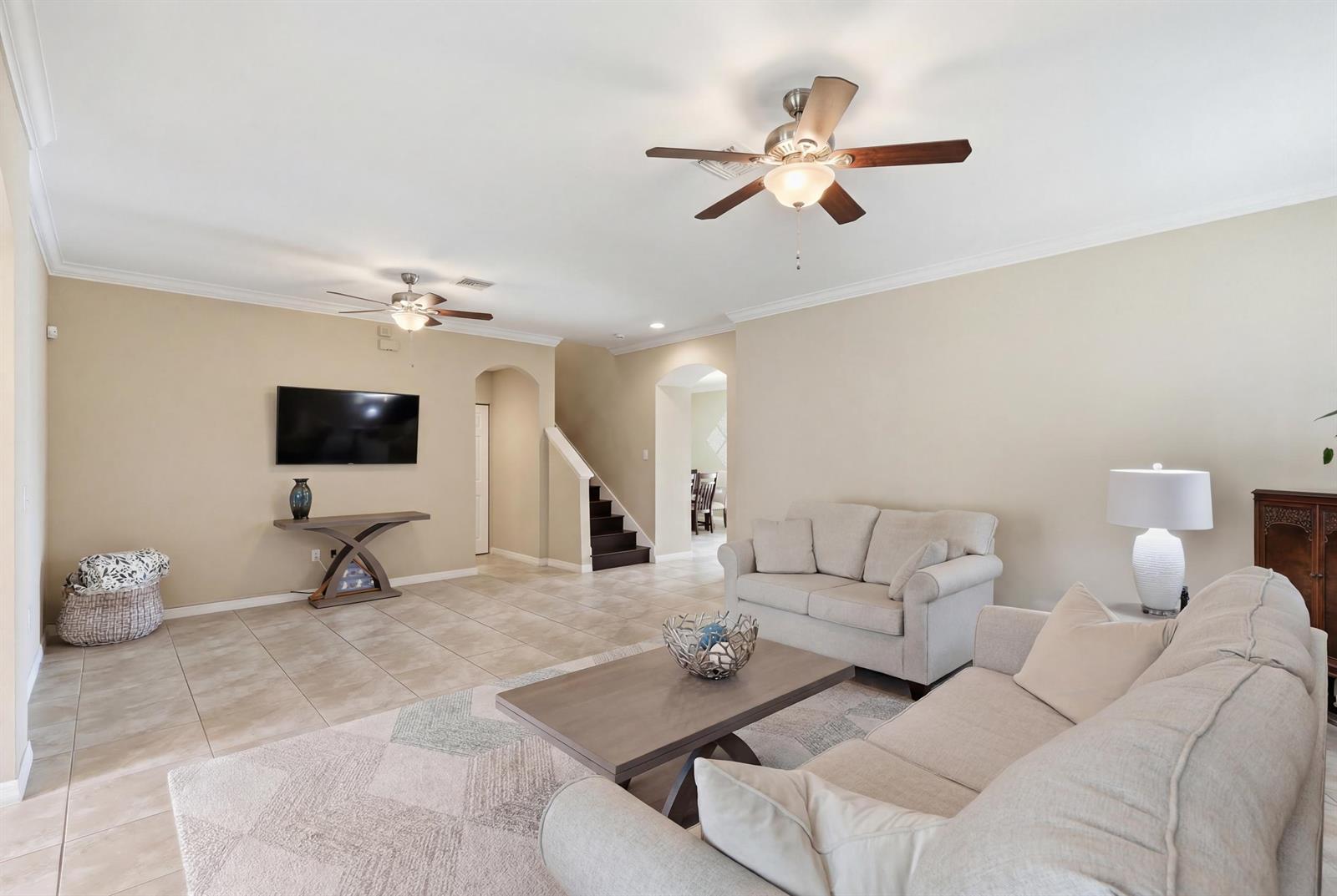 A living room features beige walls, tile flooring, two ceiling fans, and neutral-colored furniture — 1517 Birdie Drive, Naples FL 34120, NAPLES, FL