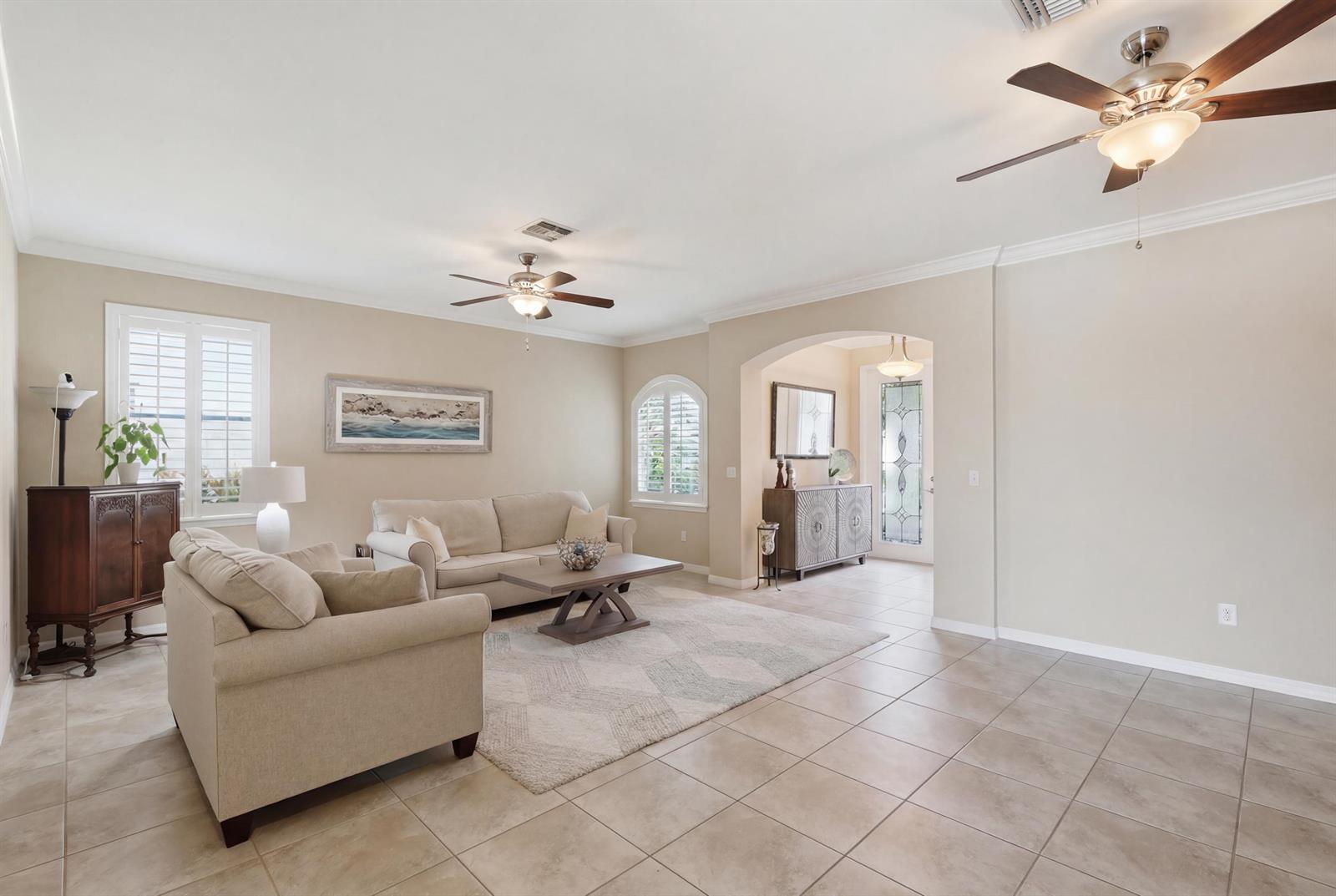 A living room with tile flooring, two ceiling fans, and a neutral-toned seating area — 1517 Birdie Drive, Naples FL 34120, NAPLES, FL