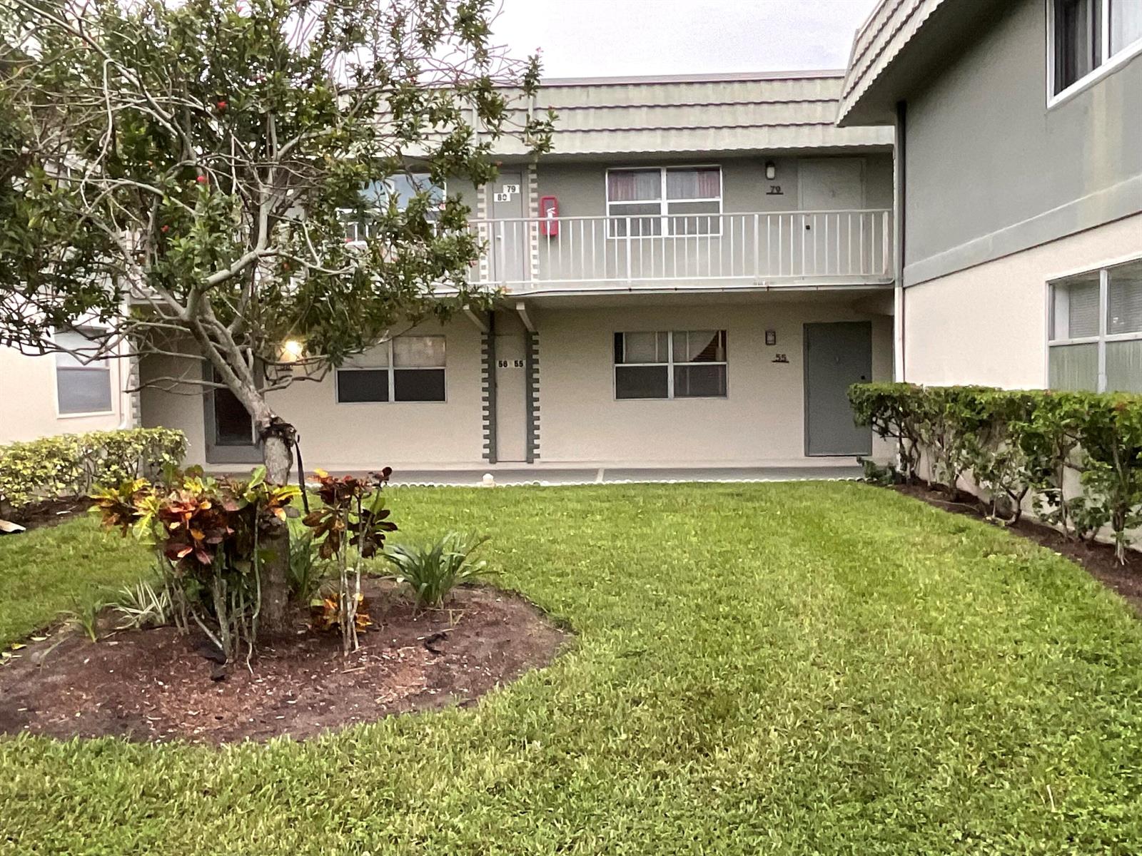 A two-story apartment building exterior with a grassy lawn and a small tree — 679 Saxony Way, Delray Beach FL 33446, DELRAY BEACH, FL