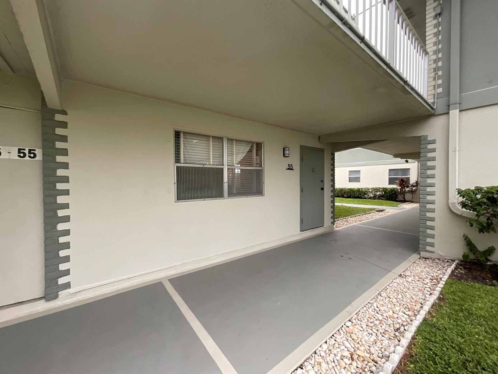 An exterior view shows a covered walkway leading to a gray door labeled 55 — 679 Saxony Way, Delray Beach FL 33446, DELRAY BEACH, FL