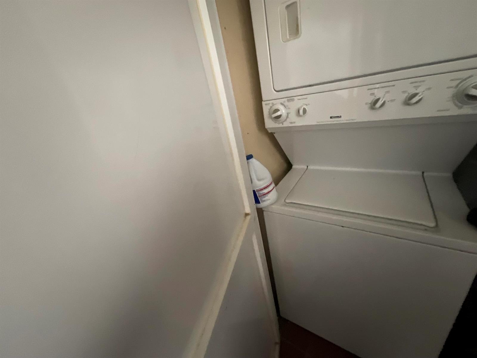 A white stacked washer and dryer unit sits in a small laundry closet — 679 Saxony Way, Delray Beach FL 33446, DELRAY BEACH, FL
