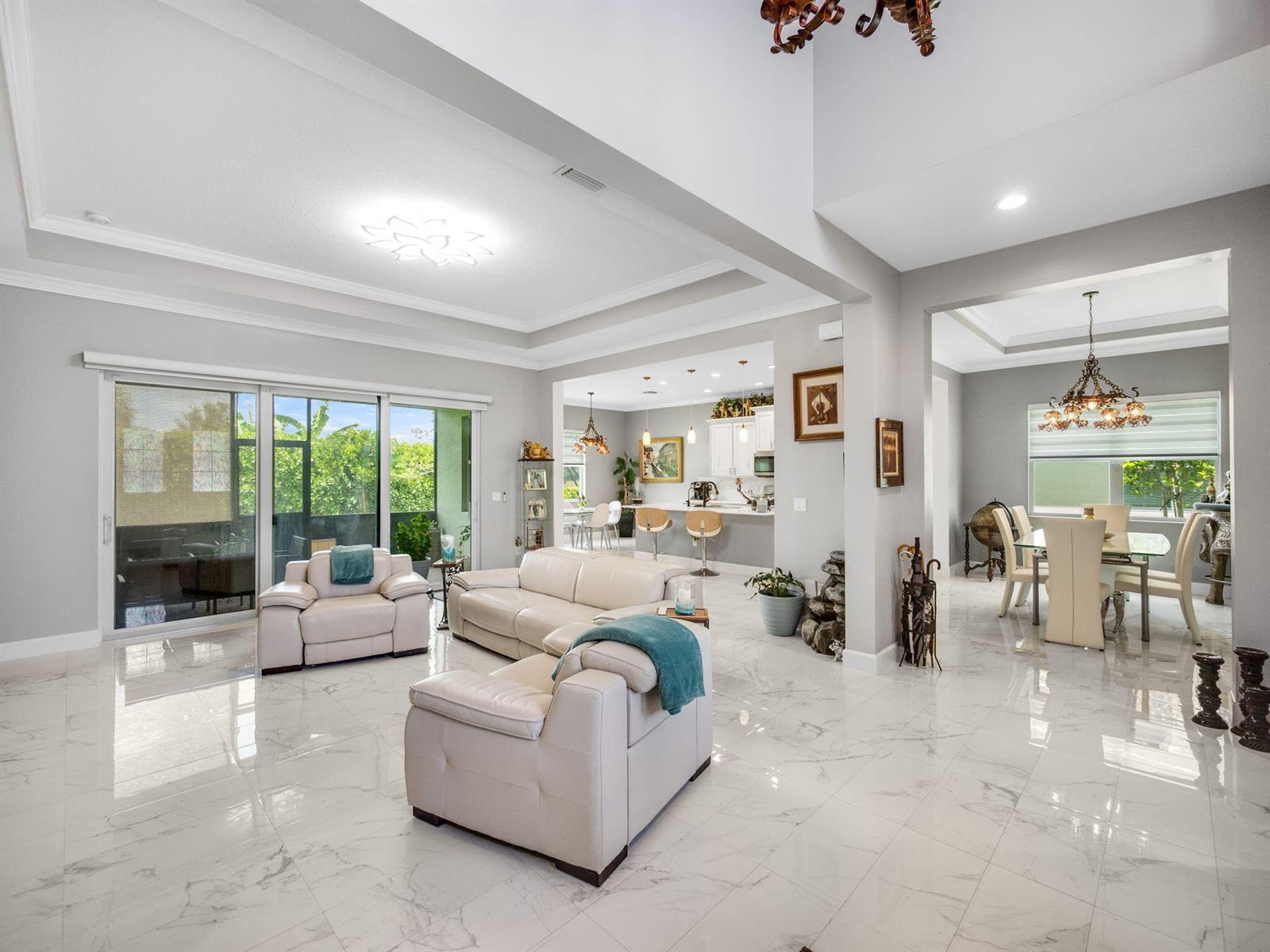 An open-concept living area features white marble tile floors, cream leather furniture, and a kitchen — 5857 Whippoorwill Circle, Westlake FL 33470, WESTLAKE, FL