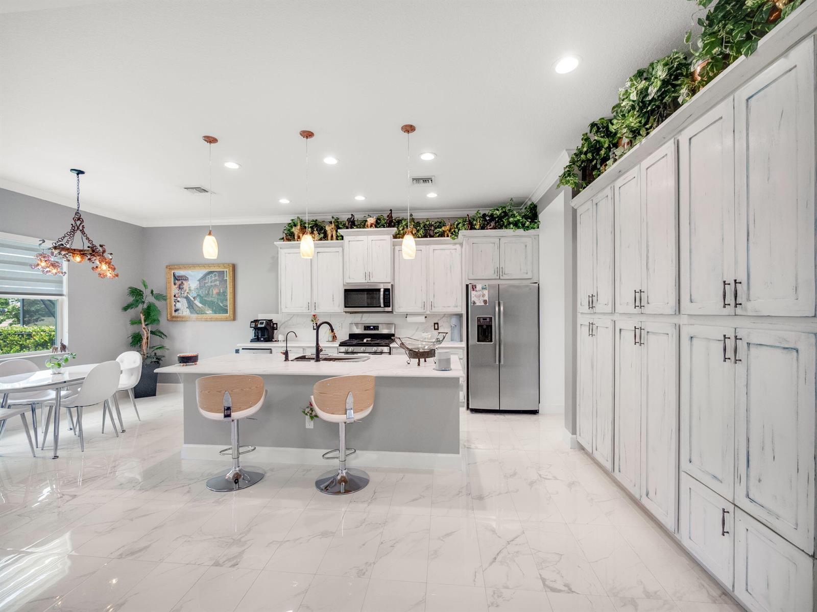 A kitchen with white distressed cabinetry, a marble-topped island, and light-colored marble tile flooring — 5857 Whippoorwill Circle, Westlake FL 33470, WESTLAKE, FL