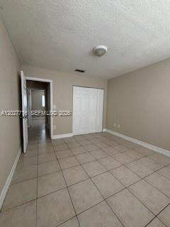 A bedroom with beige walls, light tile flooring, and a white closet with sliding doors — 5694 W 25th Ct # 5694, Hialeah FL 33016, HIALEAH, FL