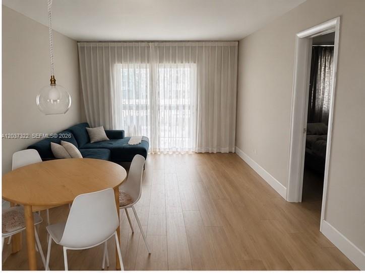 A living and dining area features light wood flooring, a blue sectional sofa, and curtains — 220 Washington Ave # 5C, Miami Beach FL 33139, MIAMI BEACH, FL