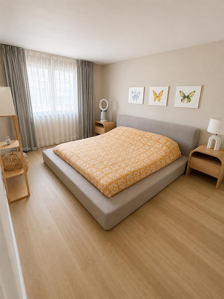A bedroom features a low-profile gray bed, light wood flooring, and three butterfly-themed wall prints — 220 Washington Ave # 5C, Miami Beach FL 33139, MIAMI BEACH, FL