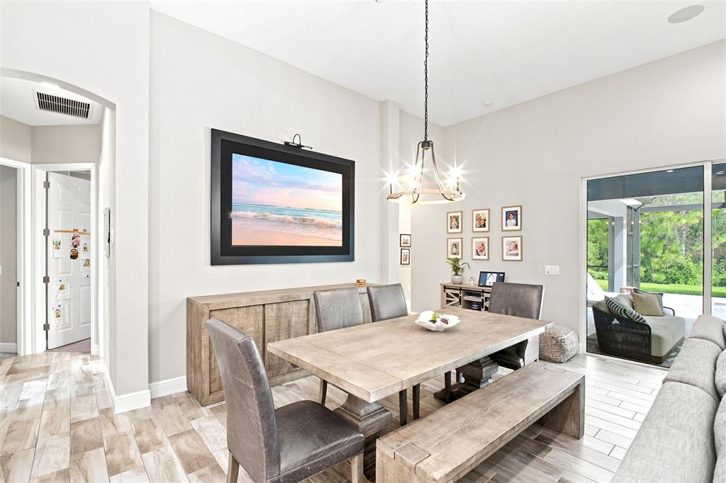 A dining room features a wooden table, bench, chairs, a sideboard, and a wall-mounted television — 4263 WOODLAND RETREAT BOULEVARD, NEW PORT RICHEY, FL