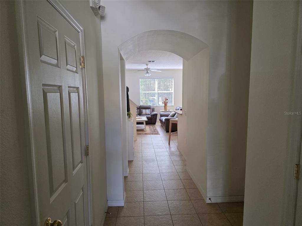 A tiled entryway leads through an arched doorway into a living room with a ceiling fan — 5160 AMBERGRIS LOOP, KISSIMMEE, FL