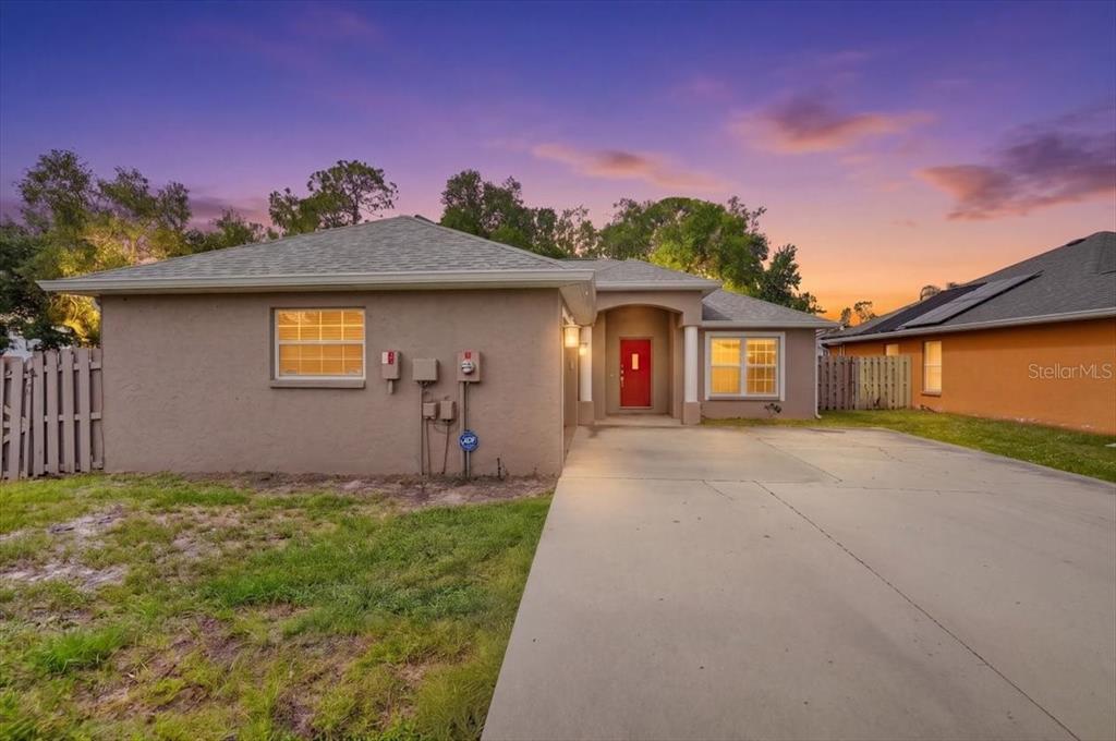 A single-story house with a tan stucco exterior, a red front door, and a concrete driveway — 1881 SUMMER WALK CIRCLE, SARASOTA, FL