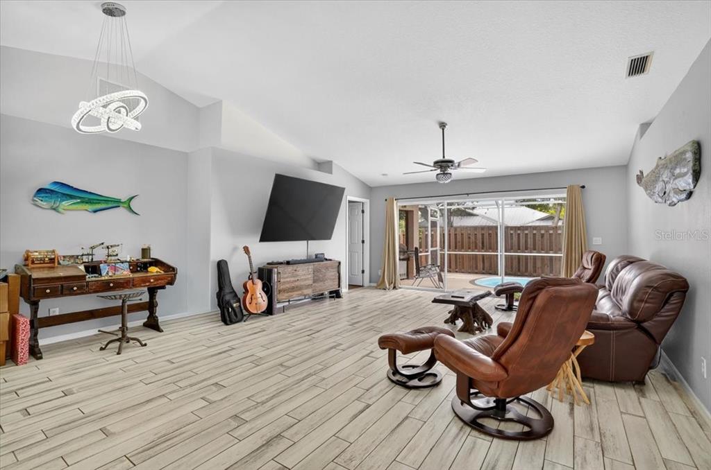 A living room features light wood-look tile floors, a vaulted ceiling, and a sliding glass door — 1881 SUMMER WALK CIRCLE, SARASOTA, FL