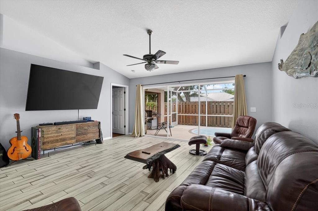A living room features light wood-look tile floors, a large television, and a sliding glass door — 1881 SUMMER WALK CIRCLE, SARASOTA, FL