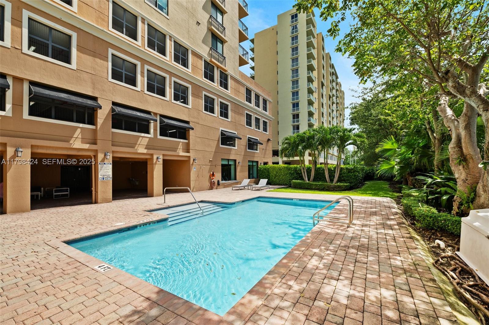 An outdoor swimming pool is situated on a brick patio beside a multi-story apartment building — 3530 SW 22nd St # 614, Miami FL 33145, MIAMI, FL