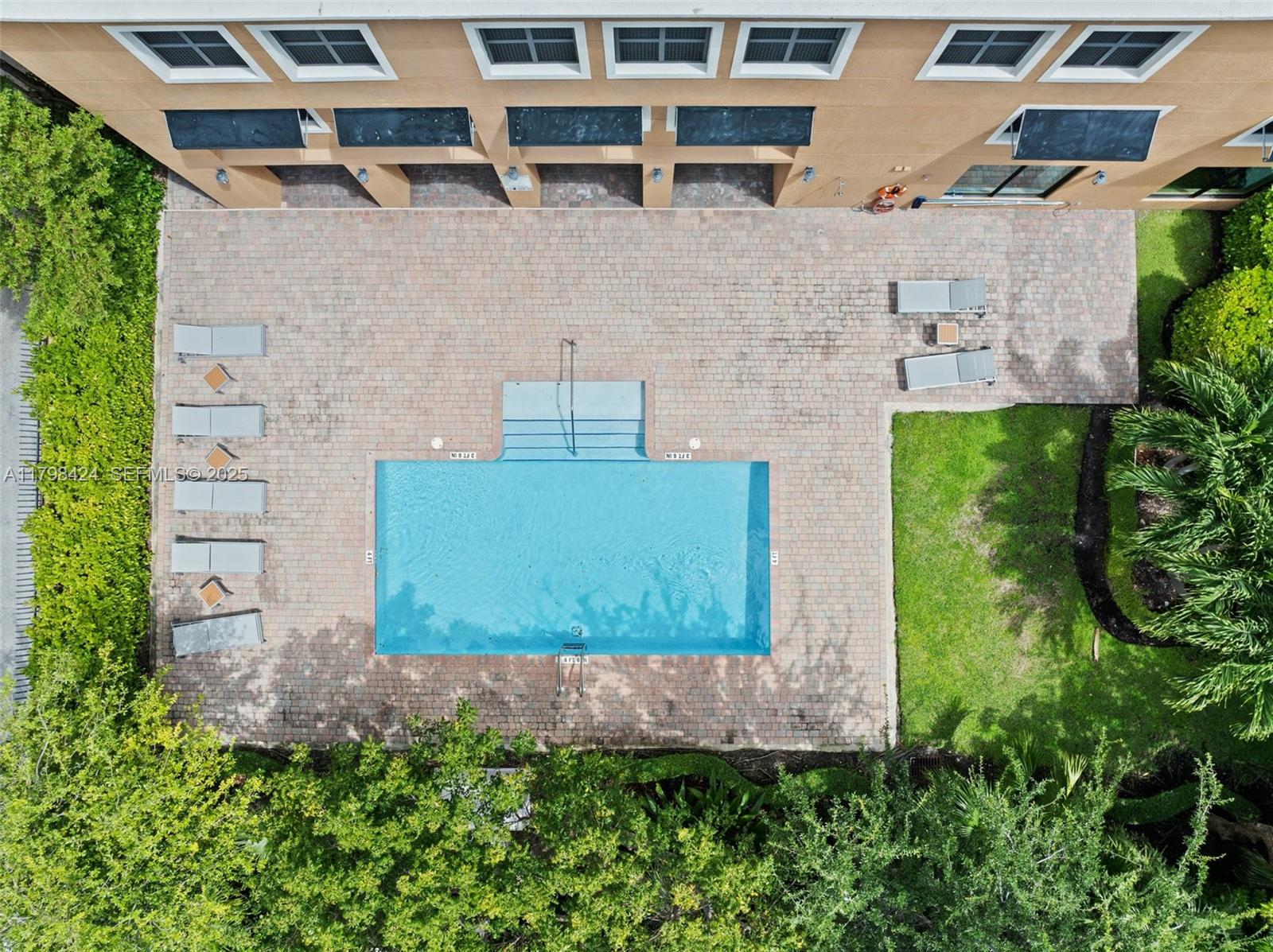 An aerial view shows a rectangular swimming pool with a patio, lounge chairs, and landscaping — 3530 SW 22nd St # 614, Miami FL 33145, MIAMI, FL