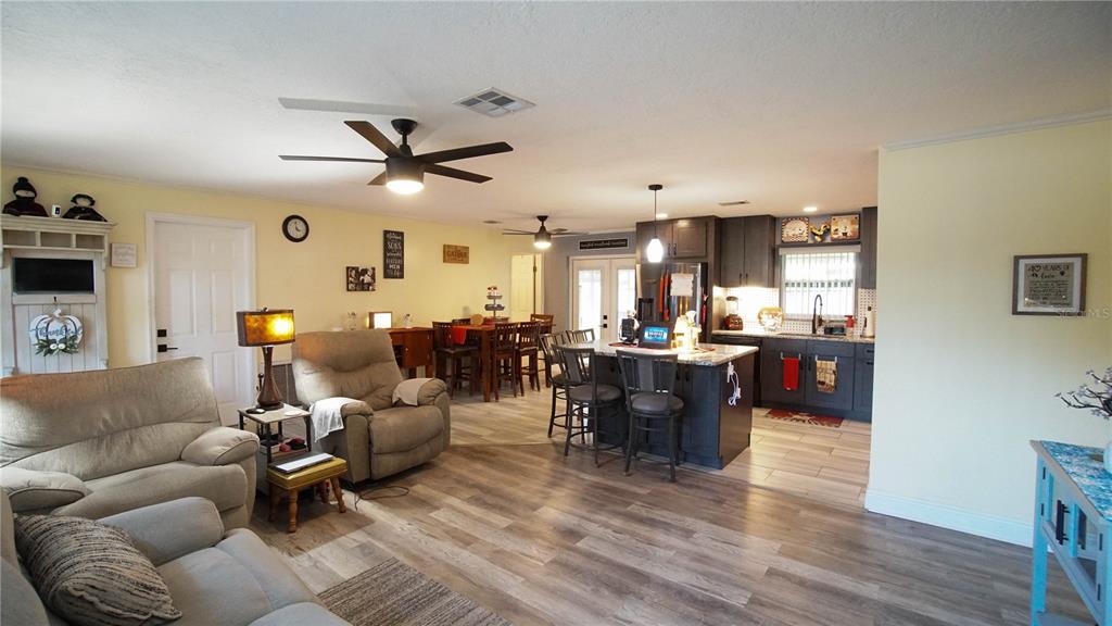 An open-concept living room and kitchen featuring wood-look flooring, a kitchen island, and ceiling fans — 2550 FULTON COURT, MELBOURNE, FL