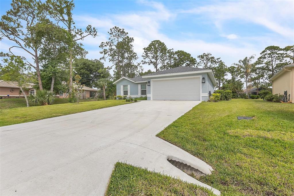 A light blue single-story house with a two-car garage and a concrete driveway — 63 PRESIDENT LANE, PALM COAST, FL