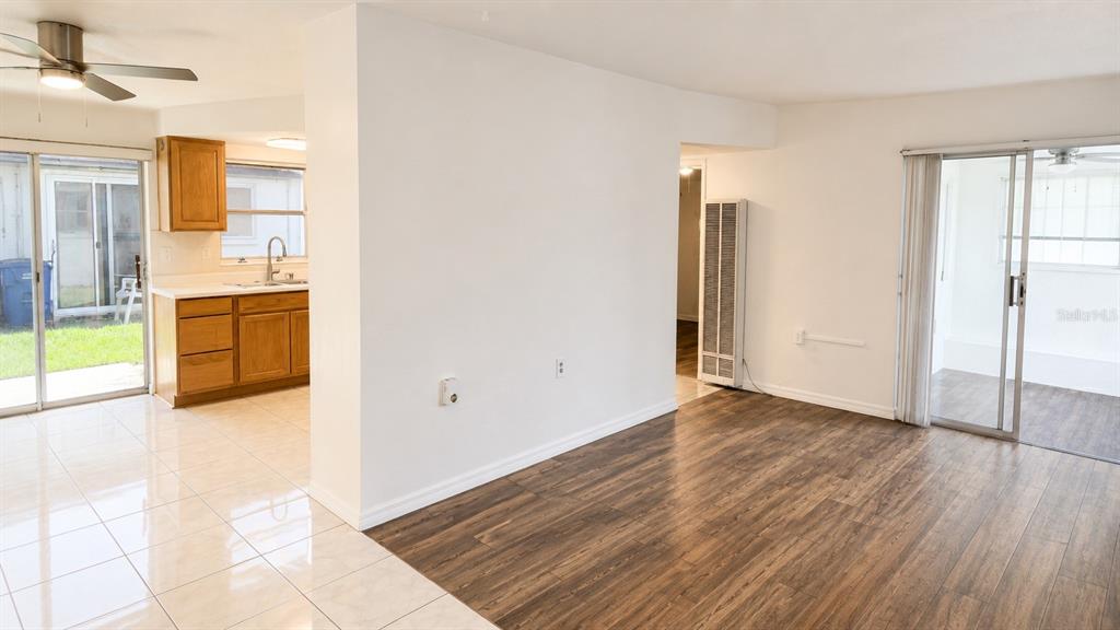 A room with wood-look flooring and a tiled kitchen area featuring wooden cabinets — 6165 58TH STREET N UNIT 3G, ST PETERSBURG, FL