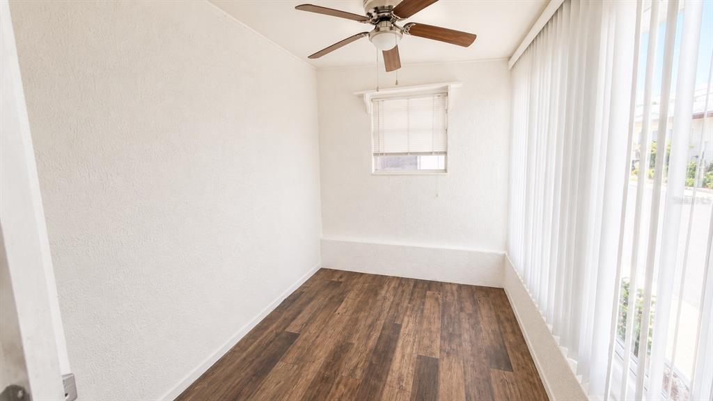 A sunroom with wood-look flooring, white walls, a ceiling fan, and vertical window blinds — 6165 58TH STREET N UNIT 3G, ST PETERSBURG, FL