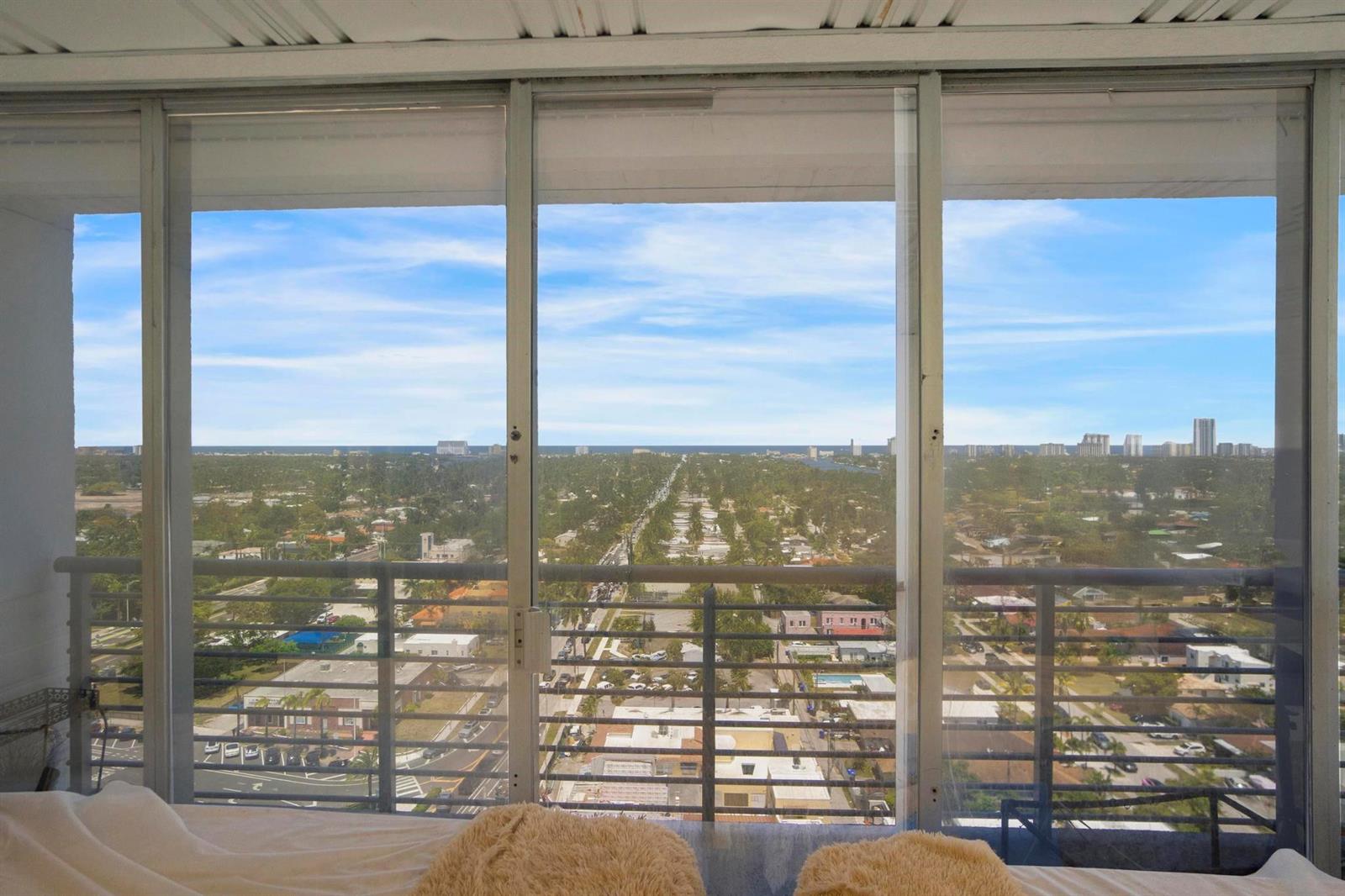 A view of a suburban landscape from a high-rise bedroom with floor-to-ceiling sliding glass doors — 1720 E Harrison Street # A, Hollywood FL 33020, HOLLYWOOD, FL