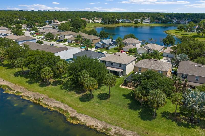 An aerial view of suburban houses with backyards facing a lake on a sunny day — PALM BAY, FL
