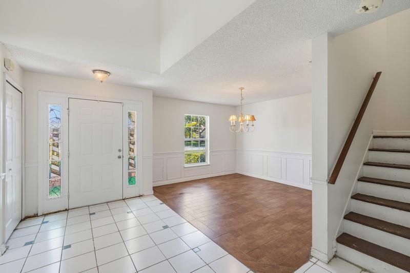 An entryway with white tile floors leads to a dining area with wood flooring — PALM BAY, FL