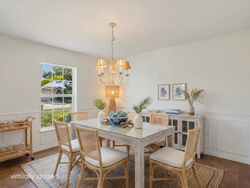 A dining room features a glass-top table, rattan chairs, a chandelier, and a sideboard — PALM BAY, FL