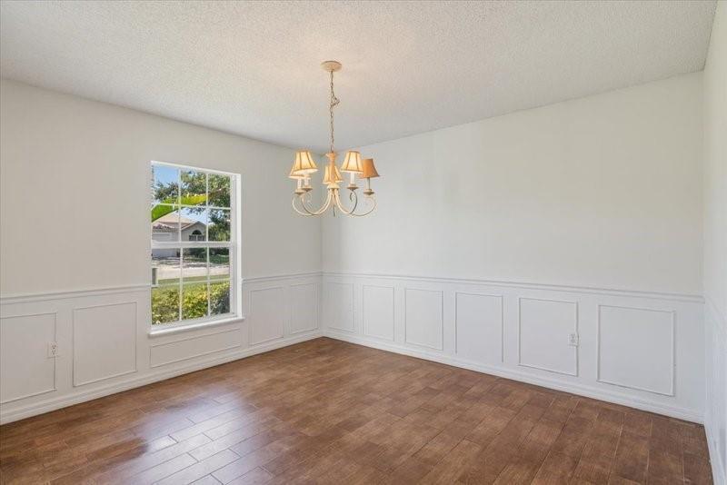 A dining room with white wainscoting, wood-look tile flooring, and a traditional chandelier — PALM BAY, FL