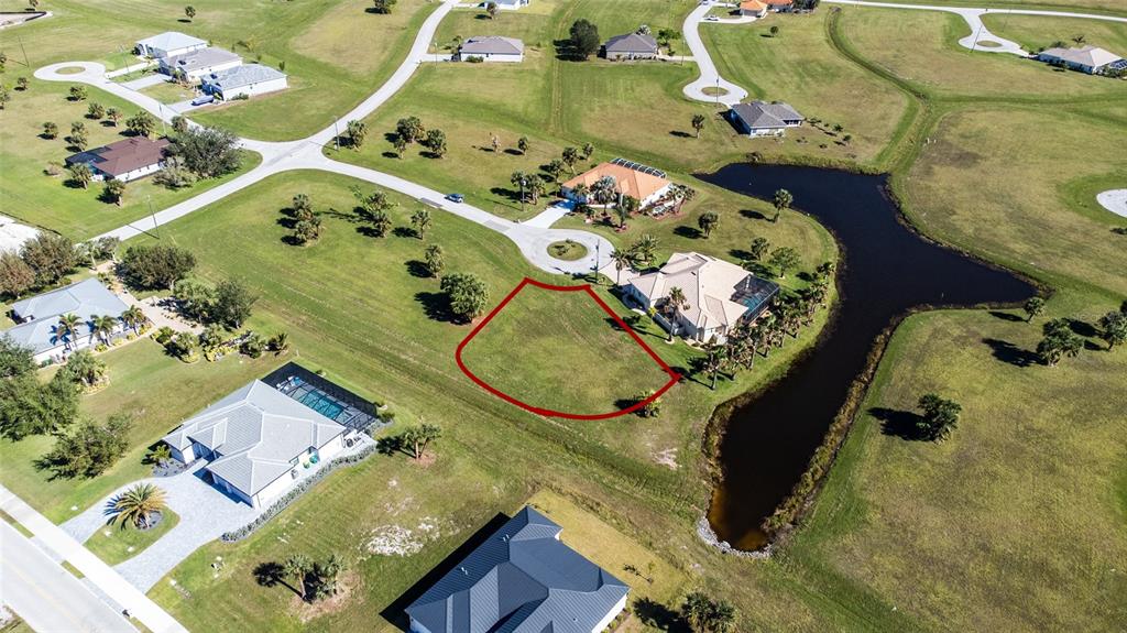 An aerial view shows a vacant residential lot outlined in red next to a pond — 16407 RABAT WAY, PUNTA GORDA, FL