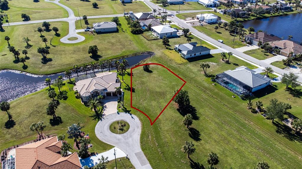 An aerial view shows a vacant residential lot outlined in red within a suburban neighborhood — 16407 RABAT WAY, PUNTA GORDA, FL