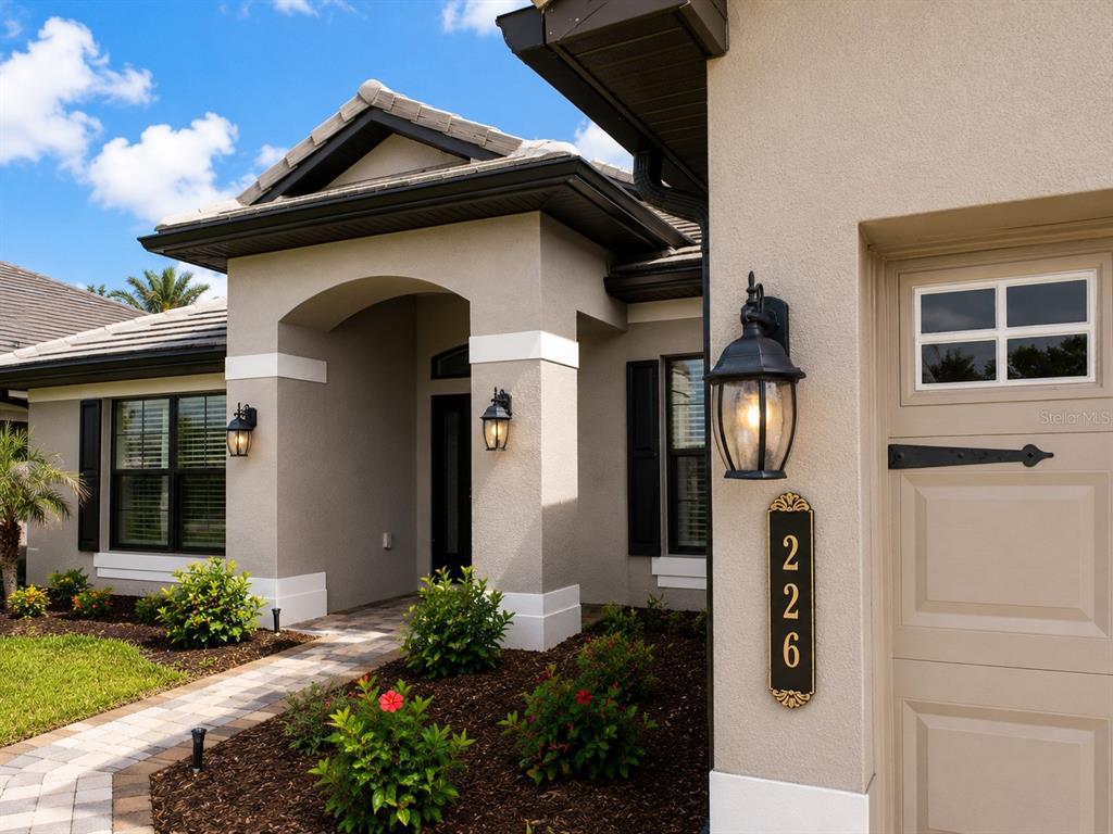 The exterior of a house features a tan stucco facade, a paved walkway, and landscaping — 226 LAKE VISTA DRIVE, AUBURNDALE, FL