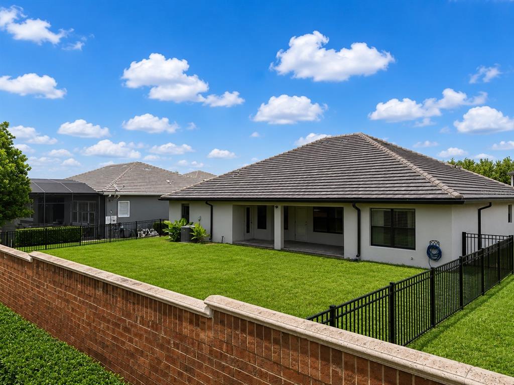 The backyard features a grassy lawn, a covered patio, and a brick perimeter wall — 226 LAKE VISTA DRIVE, AUBURNDALE, FL