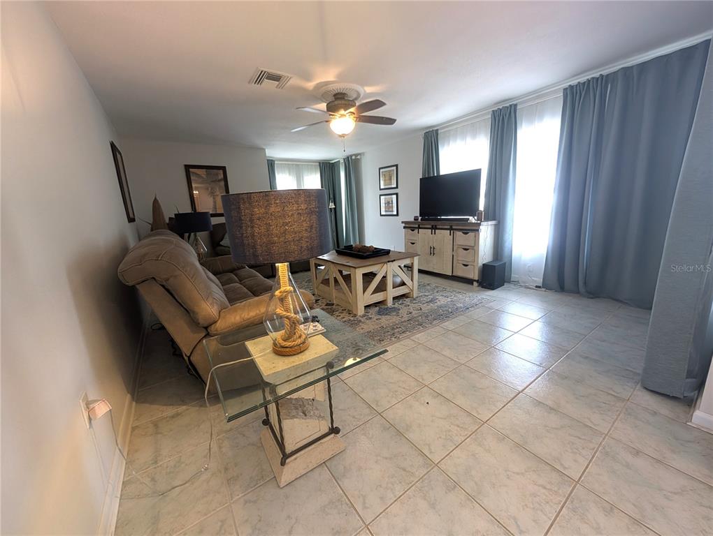 A living room features tile flooring, a beige sofa, a glass side table, and a television console — 50 CADDY ROAD, ROTONDA WEST, FL