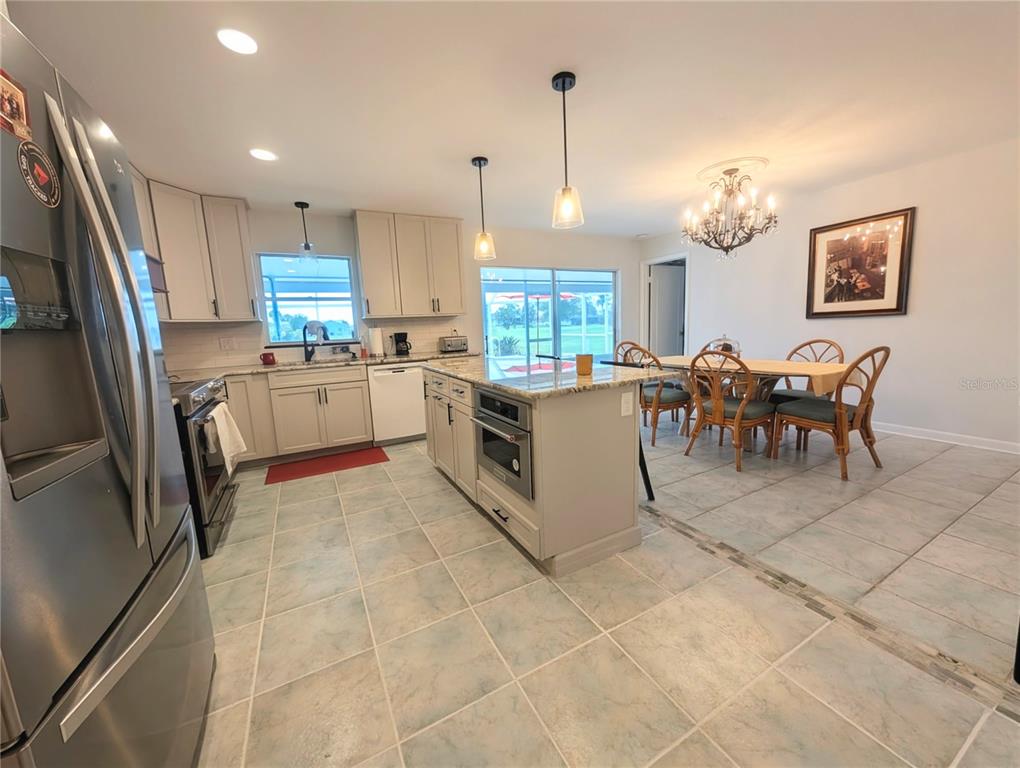 A kitchen with light-colored cabinets, a central island, and an adjacent dining area with tile — 50 CADDY ROAD, ROTONDA WEST, FL