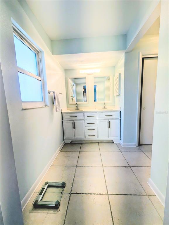 A bathroom features a double vanity with white cabinets, two mirrors, and light-colored floor tiles — 50 CADDY ROAD, ROTONDA WEST, FL