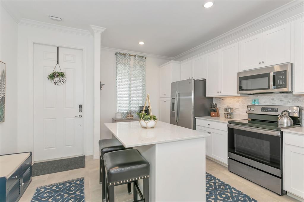 A kitchen features white cabinets, stainless steel appliances, a center island, and a white door — 18028 GAWTHROP DRIVE UNIT 403, BRADENTON, FL