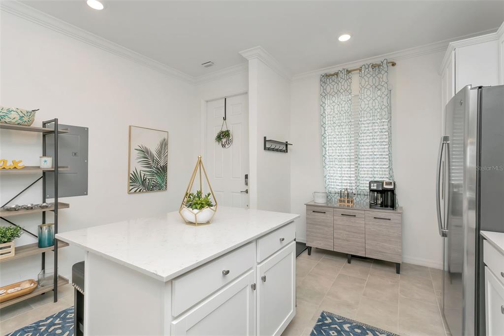 A kitchen features a white island, light wood cabinetry, stainless steel appliances, and tile flooring — 18028 GAWTHROP DRIVE UNIT 403, BRADENTON, FL