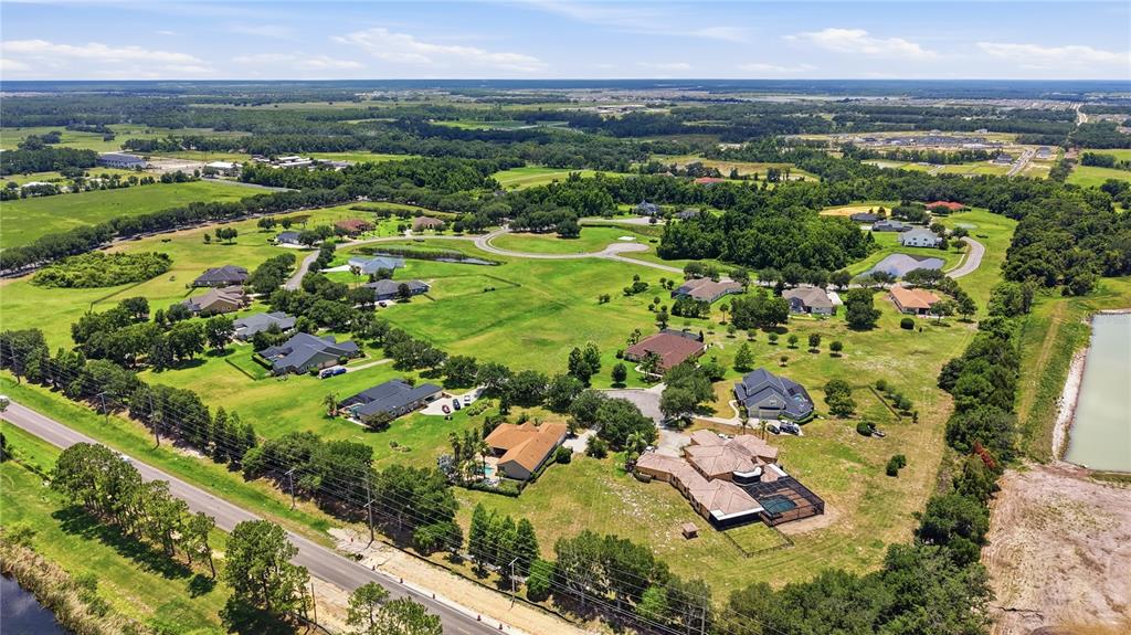 An aerial view shows several houses situated on large, grassy lots in a rural area — 9853 PREAKNESS STAKES WAY, DADE CITY, FL