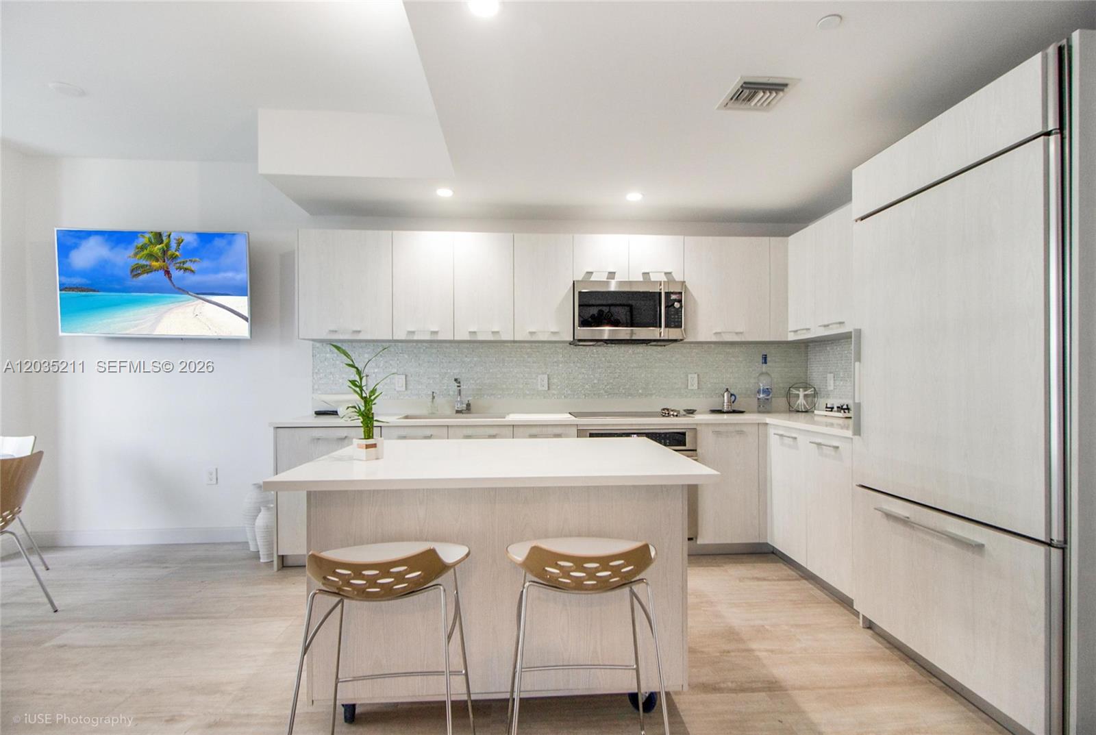 A modern kitchen features light wood cabinetry, a white island, and stainless steel appliances — 55 SW 9th St # 3802, Miami FL 33130, MIAMI, FL