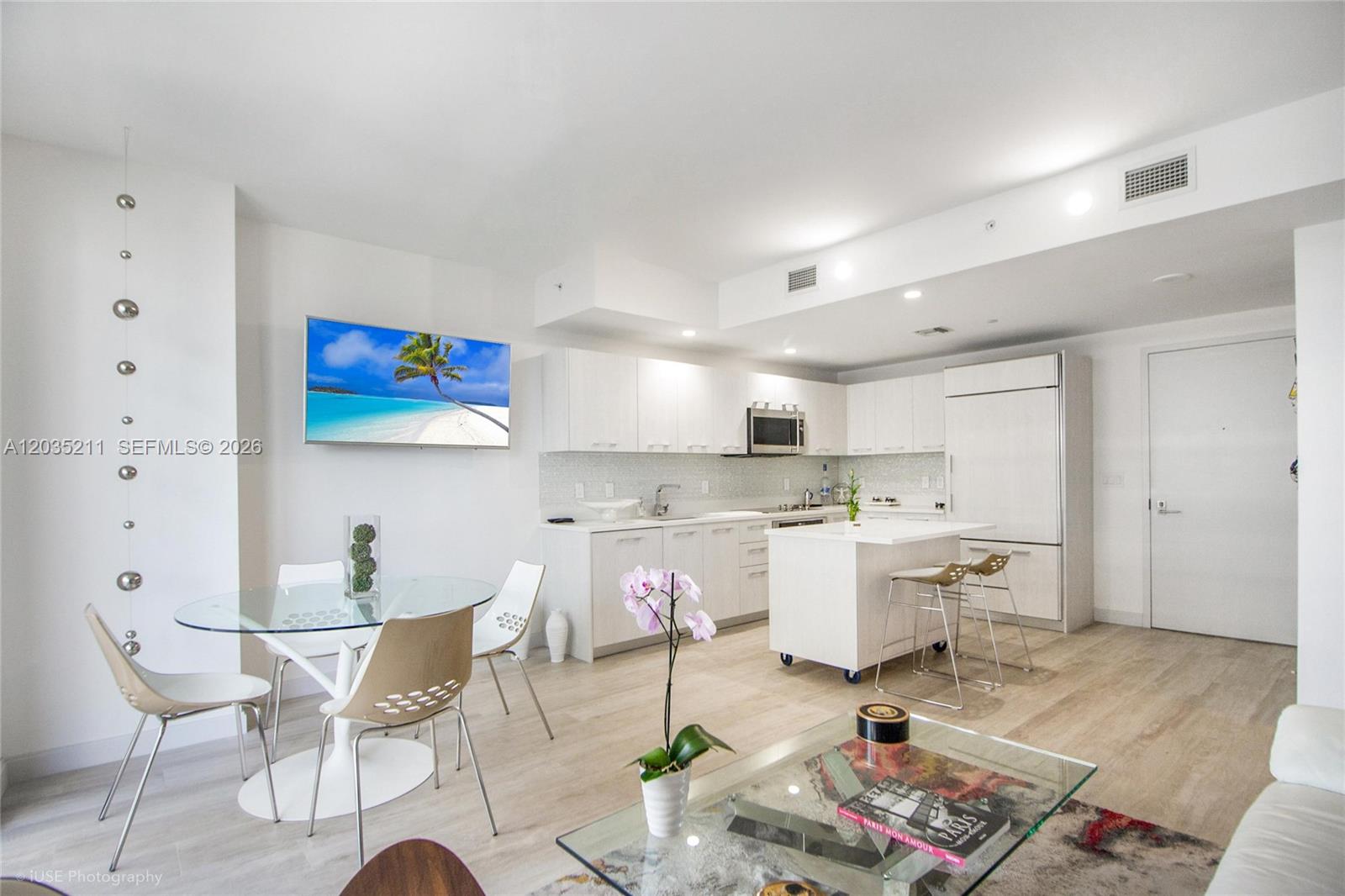 A modern kitchen and dining area feature white cabinetry, a glass table, and light flooring — 55 SW 9th St # 3802, Miami FL 33130, MIAMI, FL